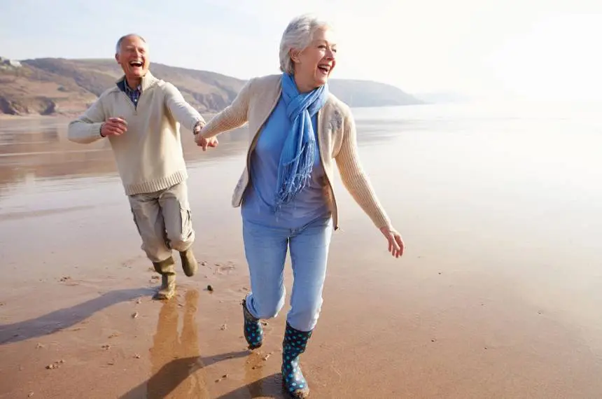 Senior couple running along winter beach