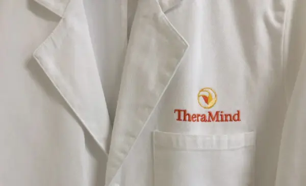 A white lab coat with the word theramind on it.