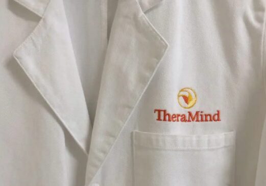 A white lab coat with the word theramind on it.